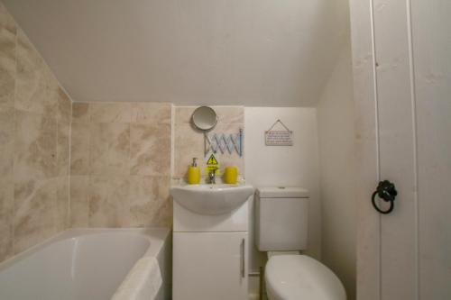 a bathroom with a tub and a toilet and a sink at Pink Cottage, Stradbroke in Stradbroke