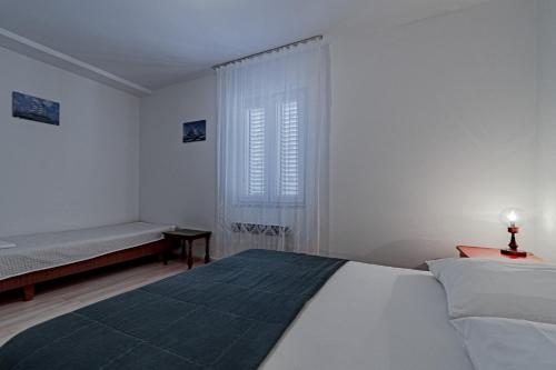a white bedroom with a bed and a window at Apartment Orebic 646b in Orebić