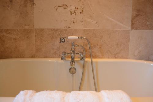 a bathroom with a bath tub with a towel at May Barn, Ixworth in Ixworth
