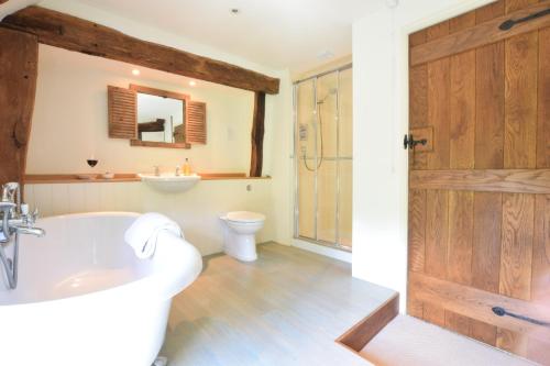 a bathroom with a tub and a toilet and a sink at Rectory Farm Cottage, Rougham in Rushbrooke