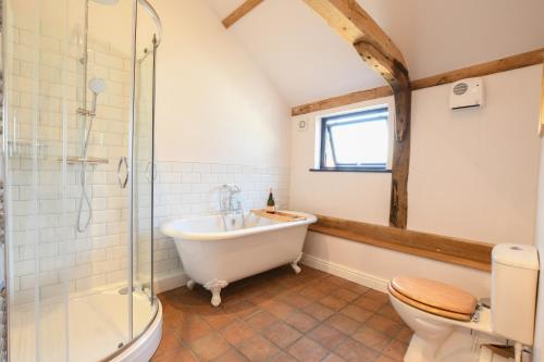 a bathroom with a tub and a toilet and a sink at Onna's Stable, Sotherton in Sotherton