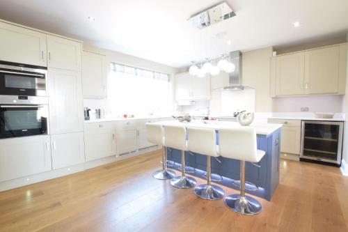 a kitchen with white cabinets and a island with bar stools at St Marys View, Southwold in Southwold