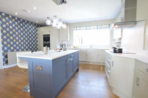 una cucina con armadi blu e bianchi e una grande finestra di St Marys View, Southwold a Southwold
