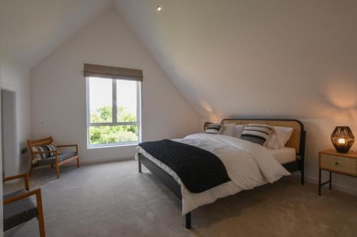 a white bedroom with a bed and a window at Salt Marsh House, Southwold in Southwold