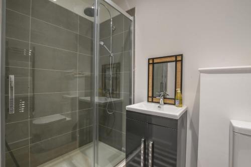 a bathroom with a shower and a sink and a mirror at Salt Marsh House, Southwold in Southwold
