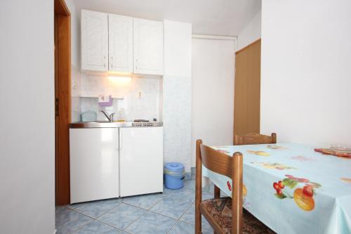 a kitchen with a white refrigerator and a table at Studio Punta kriza 383b in Punta Križa