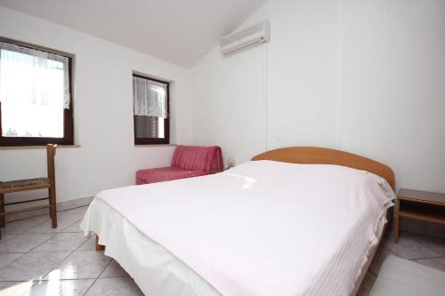 a bedroom with a white bed and a red chair at Apartments with a parking space Punta kriza, Cres - 383 in Punta Križa