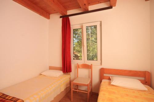 Žman的住宿－Secluded fisherman's cottage Krknata, Dugi otok - 397，客房设有两张床、一把椅子和窗户。