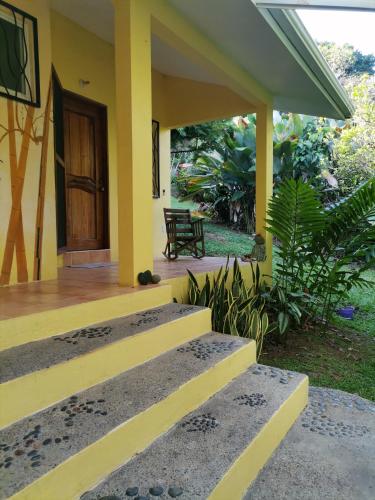 a yellow house with a wooden door and stairs at Mira Olas Cabins in Pavones