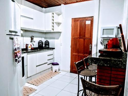 una pequeña cocina con armarios blancos y una puerta roja en Casa de Temporada no Centro de Pedra Azul, en Pedra Azul