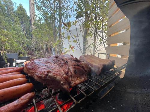 a steak and hot dogs on a grill at Lodge Los Alerces in Los Muermos