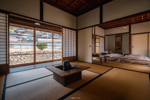 a room with a bed and a table and windows at Japan's oldest remaining company housing in Ikuno