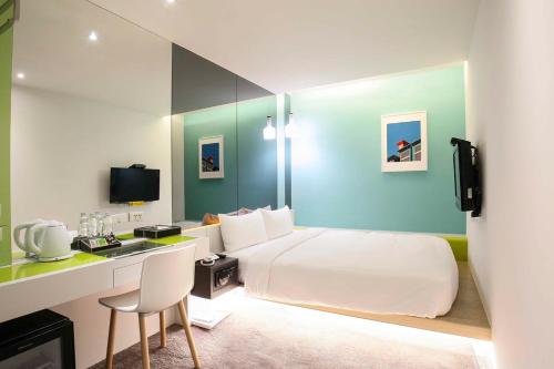 a hotel room with a white bed and a desk at CityInn Hotel Taipei Station Branch III in Taipei