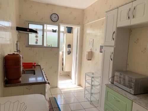 una cucina con bancone e lavandino e una finestra di APARTAMENTO NA PRAIA GRANDE A 200 MÉTROS DA PRAIA, CONFORTÁVEL ESPAÇOSO WIFI 350 Mega TV Claro, ÓTIMA LOCALIZAÇÃO a Praia Grande