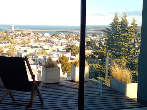 a chair on a balcony with a view of a city at HOMU DEP - Puerto deseado in Puerto Deseado