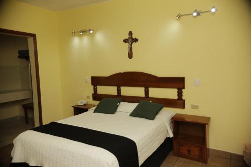 a bedroom with a bed with a cross on the wall at Hotel Posada Santa Fe Sabinas in Sabinas