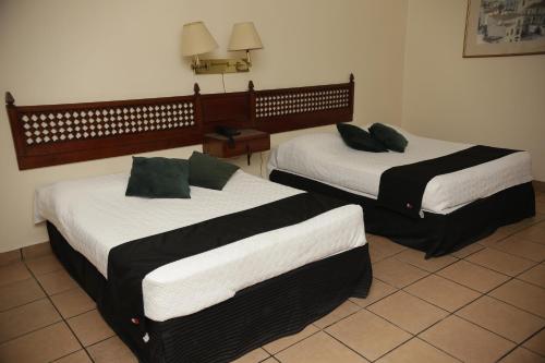 two beds in a hotel room withskirts at Hotel Posada Santa Fe Sabinas in Sabinas