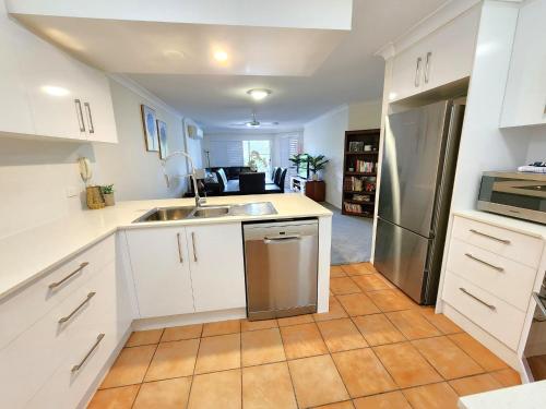 a kitchen with white cabinets and a stainless steel refrigerator at Fairways Golf & Beach Retreat Bribie Island in Woorim