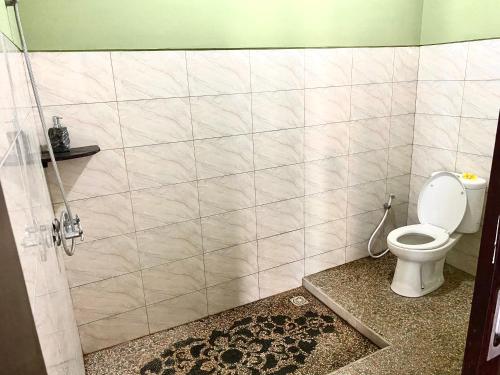 ein Bad mit einem WC und einer gefliesten Wand in der Unterkunft Lakromo Amed Homestay in Amed