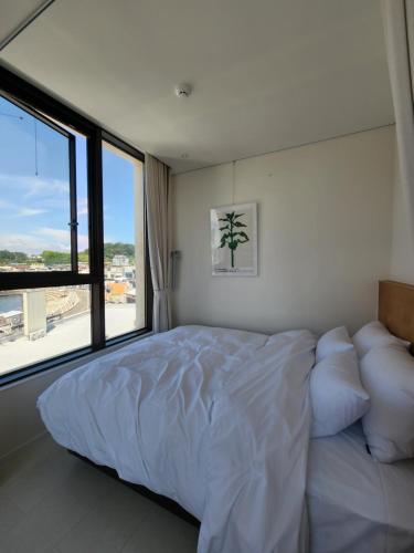 a bedroom with a large bed and a large window at Bau Haus in Sokcho