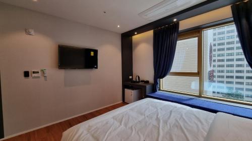 a bedroom with a bed and a tv and a window at Gold Stone Hotel in Busan