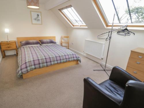 Schlafzimmer mit einem Bett, einem Stuhl und Fenstern in der Unterkunft Bryn Dedwydd Farmhouse in Pentrefoelas