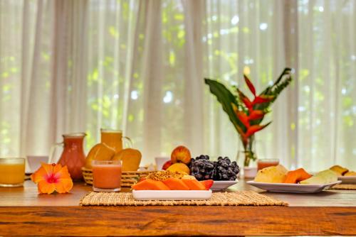a table topped with plates of fruit and juice at CasaLô Hotel in Jericoacoara