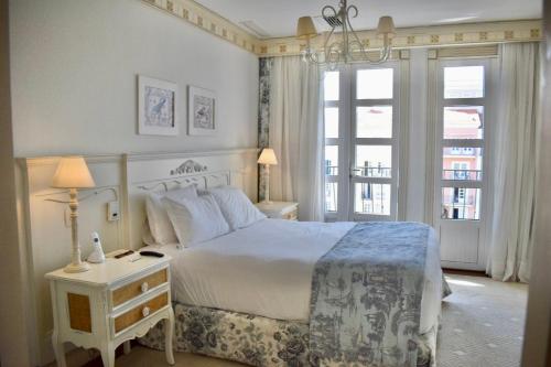 a bedroom with a white bed and a chandelier at Il Campanario - Cobertura in Florianópolis