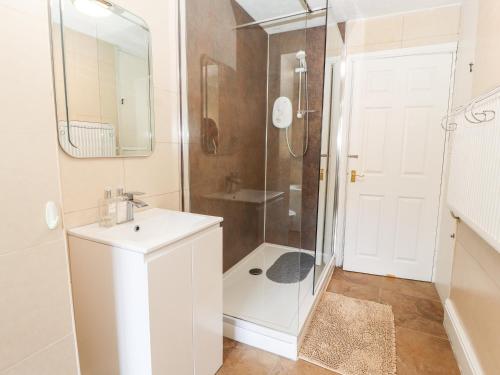 a white bathroom with a shower and a sink at Riverlea in Rhyl