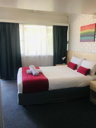 a bedroom with a large bed with red pillows at Kaputar Motel in Narrabri