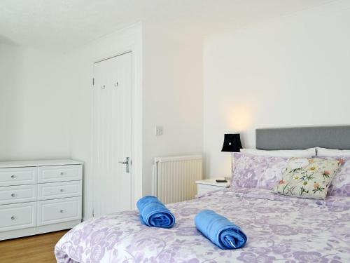 a bedroom with a bed with blue pillows on it at Ty Bryn Cottage in Kenfig Hill