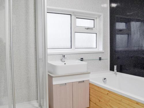 a bathroom with a sink and a window and a tub at Ty Bryn Cottage in Kenfig Hill