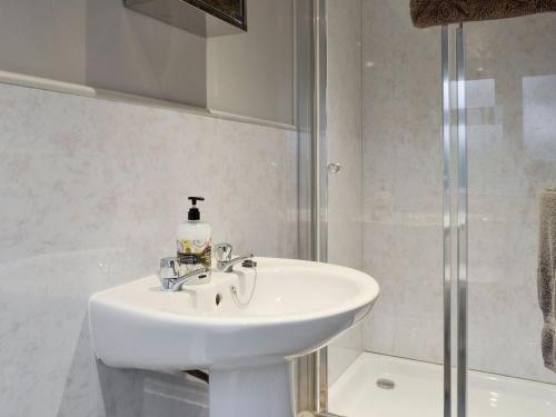 a white bathroom with a sink and a shower at Penlon in Abererch