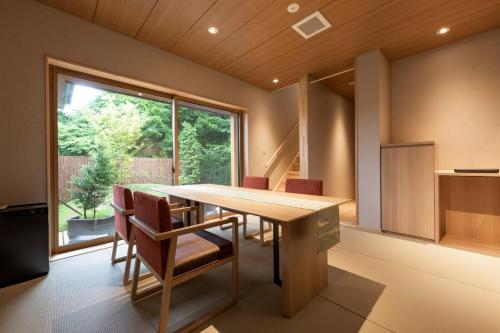 ein Esszimmer mit einem Holztisch und Stühlen in der Unterkunft 八海 木花館 in Oshino