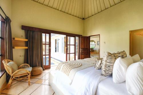 a bedroom with a large bed and a balcony at Casa Benita By Bracha Villas Management in Seminyak