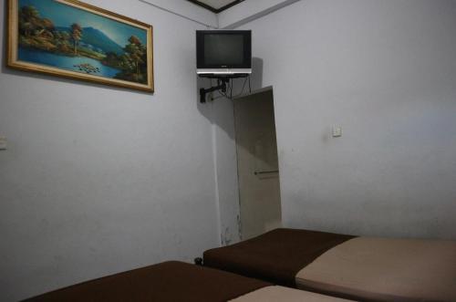 a small room with two beds and a tv on the wall at Hotel Diana 1 in Denpasar