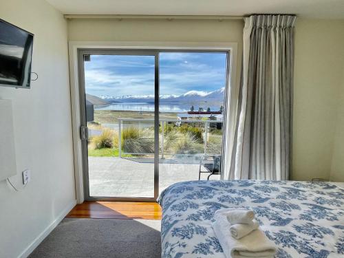 a bedroom with a bed and a sliding glass door at Antair Lakeview Lodge in Lake Tekapo