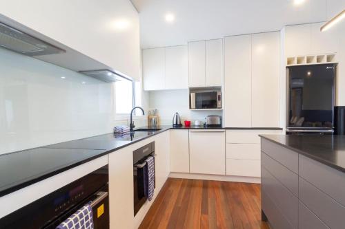 a kitchen with white cabinets and black counter tops at Antair Lakeview Lodge in Lake Tekapo