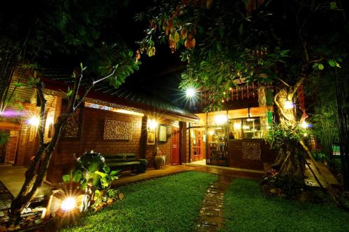 a house with lights in the yard at night at Irawadee Resort in Mae Sot