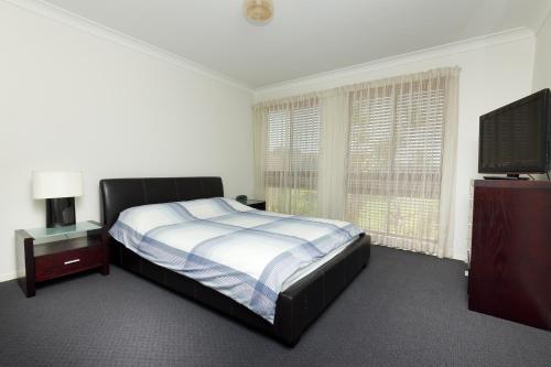 a bedroom with a bed and a flat screen tv at LAKE HOUSE ON ELOUERA in Forster