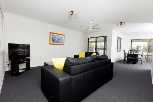 a living room with a black couch and a tv at Lake House on Elouera in Forster