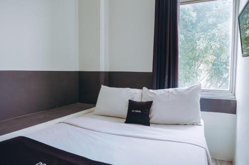 un letto con lenzuola e cuscini bianchi accanto a una finestra di DS Colive Peterongan a Jomblang
