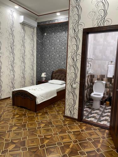 a bedroom with a bed and a toilet and a mirror at FIRDAVS HOTEL in Navoi