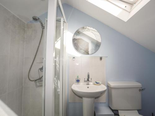a bathroom with a sink and a toilet and a mirror at Machlud Ynys in Y Felinheli