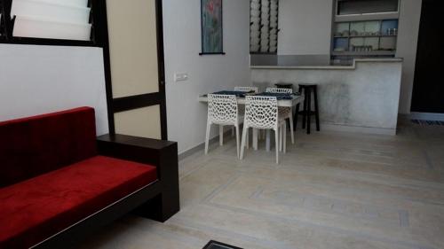 a living room with a couch and a table and chairs at Auromode Apartments Auroville in Auroville