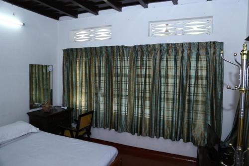a bedroom with a bed and a window with curtains at Aqualillies Water Front Heritage Homestay in Kumarakom