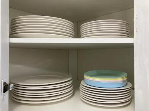 a stack of plates on a shelf in a cabinet at Sweet 5 bedrooms single house in Hinton in Hinton