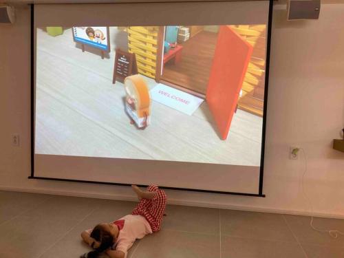 a child laying on the floor in front of a projector screen at GuReung YeonGa in Gyeongju