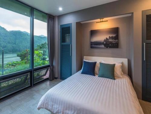 a bedroom with a large bed and a large window at Riversky Pension in Gapyeong
