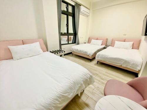 two beds in a room with pink chairs at 金門禧樂民宿 in Shan-ch'ien